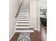 View of a staircase with hardwood treads, white risers, and a decorative carpet runner at 7691 Cabrini Pl, Fairburn, GA 30213