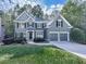 Two-story home with lush green grass, mature trees, and a long driveway leading to an attached two-car garage at 907 Fox Croft Pl, Canton, GA 30114
