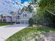 Two-story home with lush green grass, mature trees, and a long driveway leading to an attached two-car garage at 907 Fox Croft Pl, Canton, GA 30114