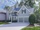 Two-story home with lush green grass, mature trees, and a long driveway leading to an attached two-car garage at 907 Fox Croft Pl, Canton, GA 30114