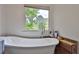 Bright bathroom featuring a freestanding tub with wood accent and a large window offering serene nature views at 2675 Dacula Ridge Dr, Dacula, GA 30019