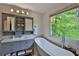 Elegant bathroom with a freestanding tub, gray vanity, and a large window overlooking greenery at 2675 Dacula Ridge Dr, Dacula, GA 30019