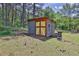 View of the property's outbuilding with yellow doors on a mature lot surrounded by lush trees and landscaping at 2675 Dacula Ridge Dr, Dacula, GA 30019