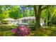 Charming single-story home with white exterior, complemented by a beautifully landscaped front yard with mature trees and colorful flowers at 754 Pinehill Se Dr, Smyrna, GA 30080