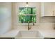 Close-up of kitchen sink with golden faucet, white countertop, and window at 754 Pinehill Se Dr, Smyrna, GA 30080