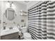 Well-lit bathroom boasts ample storage, round mirror, and shower with striped curtain at 1763 Hearthstone Cir, Lawrenceville, GA 30043