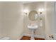 Elegant powder room with pedestal sink, decorative mirror, and stylish lighting at 1548 Valley Reserve Nw Ct, Kennesaw, GA 30152