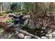 Backyard water feature with rock-lined waterfall and lush, natural landscaping at 1548 Valley Reserve Nw Ct, Kennesaw, GA 30152