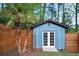 Backyard shed with white doors and blue siding, nestled between a wood fence and lush palm trees at 2895 Dunnington Cir, Atlanta, GA 30341