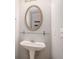Stylish bathroom featuring a pedestal sink, oval mirror, and sleek fixtures, creating a spa-like retreat for relaxation at 1728 Devon Sw Dr, Atlanta, GA 30311