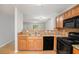 Open kitchen with wood cabinets, granite countertops, black appliances, and a bar top that opens to the living room at 1728 Devon Sw Dr, Atlanta, GA 30311
