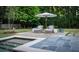 Relaxing backyard with a patio area, lounge chairs, umbrella, lush greenery, and a pristine pool at 2979 Ridgewood Nw Rd, Atlanta, GA 30327