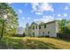 Exterior view of the home's backyard with lush grass, trees, and cloud skies at 2130 Boulder Gate Dr, Ellenwood, GA 30294