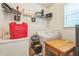 A laundry room with white washer and dryer units, small wood table, and a wire shelf at 2130 Boulder Gate Dr, Ellenwood, GA 30294
