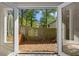 View through open doors of a fenced backyard with a brick garden, tree, and a grassy area at 3326 Northcrest Rd # C, Atlanta, GA 30340