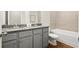 Modern bathroom features a double vanity with granite countertop and a tub with tiled walls at 877 Pensive Run, Dacula, GA 30019
