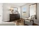 A bedroom featuring a large dresser, mirror, and picture window overlooking a leafy yard at 877 Pensive Run, Dacula, GA 30019