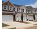 Row of townhouses featuring brick and siding exteriors, two-car garages, and meticulously landscaped front yards at 877 Pensive Run, Dacula, GA 30019