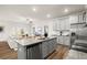 The Kitchen has gray cabinets, stainless appliances, granite countertops, hardwood floors with an open floorplan to the living room at 877 Pensive Run, Dacula, GA 30019