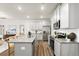 Open concept kitchen features stainless steel appliances, granite countertops, gray cabinets and a large island overlooking the living space at 877 Pensive Run, Dacula, GA 30019