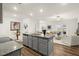 The open kitchen flows into the living room and features gray cabinets, stainless appliances, and granite countertops at 877 Pensive Run, Dacula, GA 30019