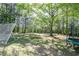 View of the backyard featuring mature trees providing shade and a trampoline for outdoor recreation at 140 Maplewood Dr, Temple, GA 30179