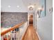 Open hallway with wood floors, brick accent wall, and view of the living room at 377 Lakeview Dr, Newborn, GA 30056
