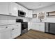 Bright kitchen featuring stainless steel appliances, white cabinetry and floating wood shelves at 9148 Homewood Dr, Riverdale, GA 30274