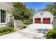 Garage exterior showing red garage doors, white siding, lush landscaping and concrete driveway at 3489 Knollwood Nw Dr, Atlanta, GA 30305