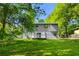 View of backyard showing the house's siding and small deck, surrounded by green lawn and trees at 6703 Cameron Rd, Morrow, GA 30260