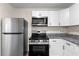 Modern kitchen featuring stainless steel appliances, granite countertops, and white cabinets at 6703 Cameron Rd, Morrow, GA 30260