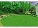 Spacious backyard featuring a well-kept lawn, stone wall, and mature trees at 2562 Red Valley Rd, Atlanta, GA 30305