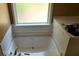 Relaxing soaking tub featuring a ledge for toiletries and a frosted window for natural light with privacy at 4175 Round Stone Dr, Snellville, GA 30039