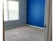 View of a carpeted bedroom with blue accent wall and window at 4175 Round Stone Dr, Snellville, GA 30039