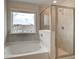 Clean bathroom with a soaking tub and a glass shower, enhanced by a natural light source from a window at 540 Teversham Dr, Mcdonough, GA 30253