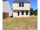 Spacious backyard with grass featuring the home's rear elevation with a door and multiple windows at 2089 Belmont Cir, Conyers, GA 30012