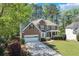 Inviting brick home featuring a manicured front lawn, attached garage, and welcoming entrance, surrounded by lush trees at 3918 Windgrove Xing, Suwanee, GA 30024