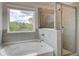 Bright bathroom featuring a tiled shower, tub, and a large window with serene outdoor views at 576 Teversham Dr, Mcdonough, GA 30253