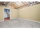 Unfinished basement area with carpeted floors, visible ceiling rafters, and a doorway to additional storage at 162 Brookhaven Way, Rockmart, GA 30153
