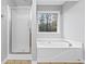Bright bathroom with a shower, soaking tub, and a window showing a peaceful wooded view at 162 Brookhaven Way, Rockmart, GA 30153