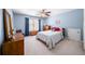 Cozy bedroom with blue walls, featuring a queen bed, ceiling fan, dresser, and a window with natural light at 3465 Summit Trl, Cumming, GA 30041