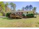 Exterior shot of the home's back yard with lush lawn, mature trees, and a deck for entertaining at 4048 Suzanne Ln, Duluth, GA 30096