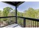 Cozy covered balcony with black metal railings offering views of the lush surrounding trees and blue skies above at 4208 Sierra Creek Ct, Hoschton, GA 30548