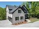 Side exterior showcases a well-maintained yard, a black garage door and complementary landscaping at 4208 Sierra Creek Ct, Hoschton, GA 30548