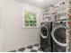 Bright laundry room with front loading washer/dryer, window, and checkerboard tile floors at 5641 Roberts Dr, Dunwoody, GA 30338