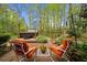 Relaxing backyard patio with orange cushioned chairs and a hot tub surrounded by lush landscaping and trees at 1410 Daley Ridge Ct, Lawrenceville, GA 30045