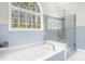 Bathroom with a soaking tub, glass shower, and view of nature outside the arched window at 1410 Daley Ridge Ct, Lawrenceville, GA 30045