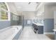 A bright bathroom with a soaking tub, glass shower, and stylish vanity with chair at 1410 Daley Ridge Ct, Lawrenceville, GA 30045