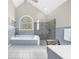 A bright bathroom with a soaking tub, glass shower, and beautiful arched window at 1410 Daley Ridge Ct, Lawrenceville, GA 30045