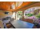 Covered outdoor patio with dining area, TV, brick arches, and access to the pool and gardens at 5473 Heyward Square Pl, Marietta, GA 30068